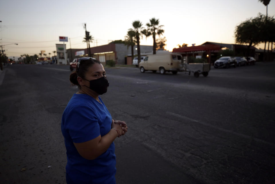 Dulce Garcia looks out on a street near her home Wednesday, July 22, 2020, in Mexicali, Mexico. Garcia, who was born in Mexico and settled with her family in California's Central Valley when she was 12, moved to Mexicali 10 years ago after her husband was deported. Garcia is uncomfortable crossing the border daily to be around COVID-19 patients but, like many others, sees no alternative to living on her U.S. salary at Mexico's cost of living. Her husband's construction job in Mexicali doesn't go far. (AP Photo/Gregory Bull)