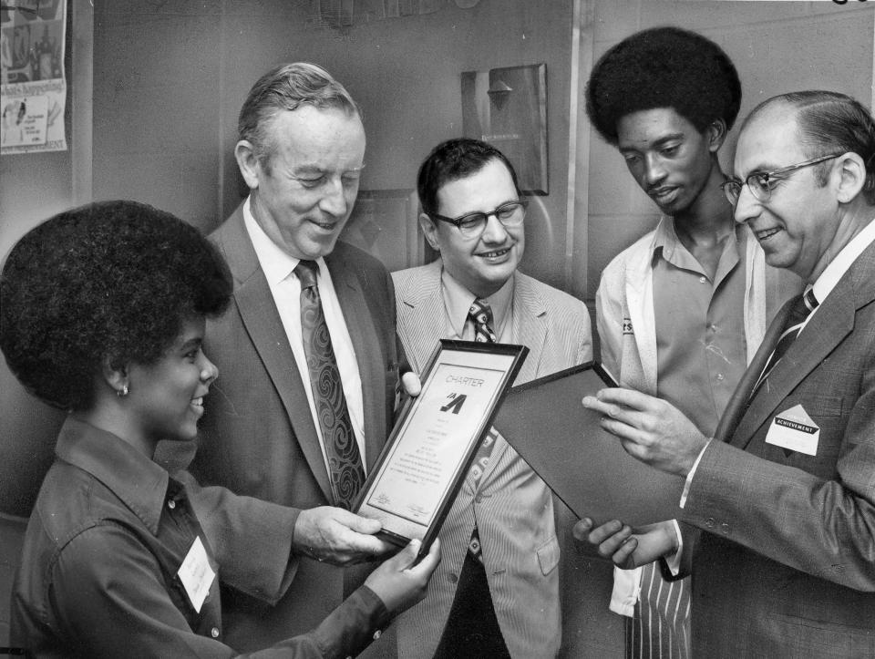 In 1971, Eugene "Gene" Shy Jr., second from right, receives a junior achievement award from Mario DiFederico, Executive VP of Firestone, right, as Mayor John Balland, center, looks on.