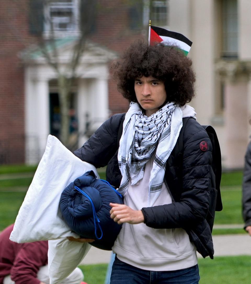 Freshman Carlo Kim, sporting a Palestinian flag in his hair, carries his pillow and sleeping bag off the Main Green at Brown University on Tuesday.