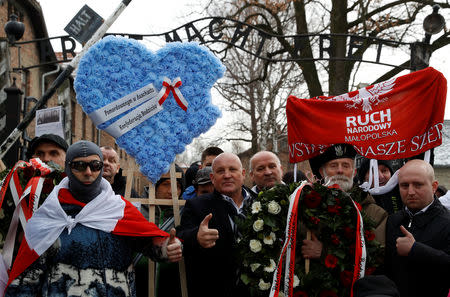 Far right activists walk past the "Arbeit Macht Frei" gate at the former Nazi German concentration and extermination camp Auschwitz, to pay tribute to Polish victims at the "death wall", during the ceremonies marking the 74th anniversary of the liberation of the camp and International Holocaust Victims Remembrance Day, in Oswiecim, Poland, January 27, 2019. REUTERS/Kacper Pempel