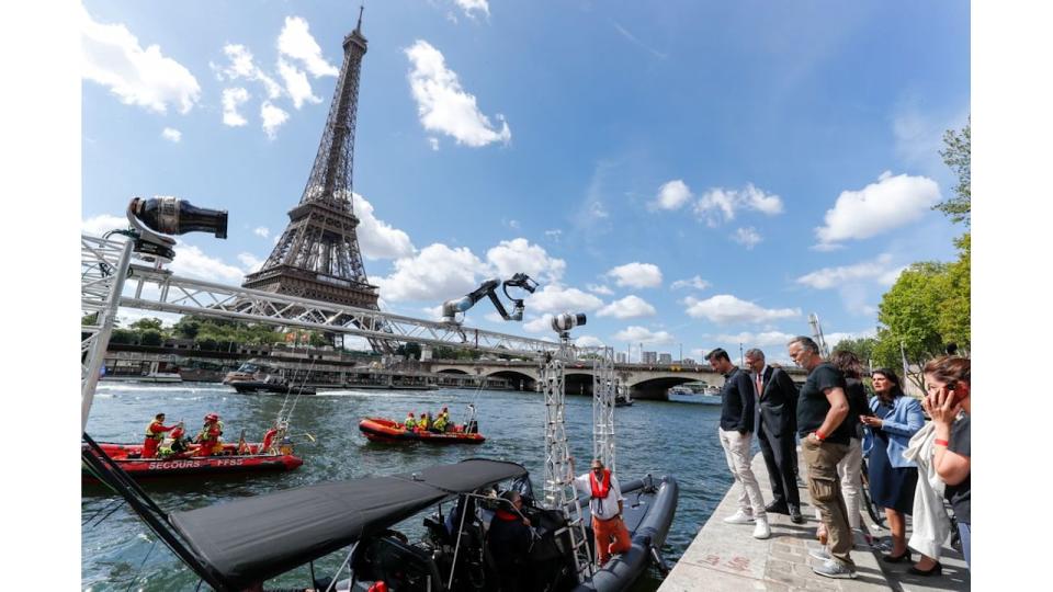 A group of people on the side of the River Seine with the Eiffel Tower in the background