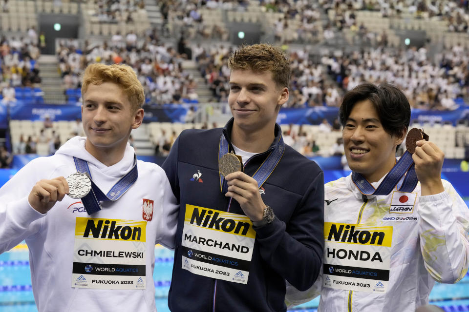 Medalists, from left to right, Krzysztof Chmielewski of Poland, silver, Leon Marchand of France, gold, and Tomoru Honda of Japan, bronze, celebrate after the medal ceremony for the men's 200m butterfly final at the World Swimming Championships in Fukuoka, Japan, Wednesday, July 26, 2023. (AP Photo/Lee Jin-man)