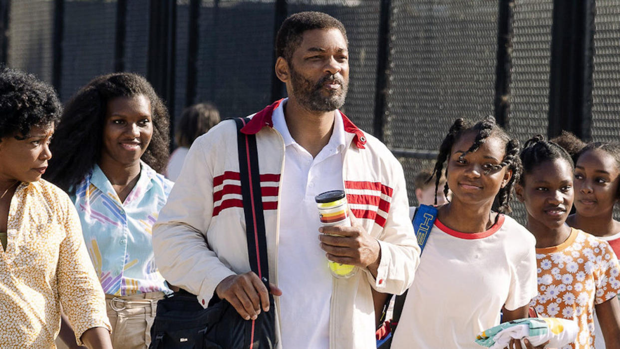  A still from the movie King Richard showing Will Smith as Richard Williams surrounded by school children. 