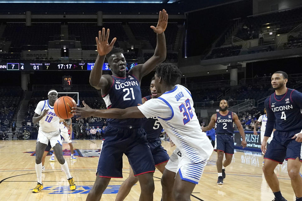 DePaul's David Jones (32) is pressured by Connecticut's Adama Sanogo (21) as he passes the ball to Yor Anei during the first half of an NCAA college basketball game Saturday, Jan. 29, 2022, in Chicago. (AP Photo/Charles Rex Arbogast)