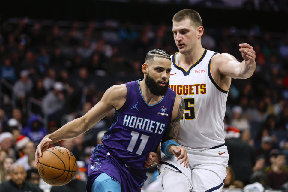 Charlotte Hornets forward Cody Martin (11) drives against Denver Nuggets center Nikola Jokic during the first half of an NBA basketball game in Charlotte, N.C., Saturday, Dec. 23, 2023. (AP Photo/Nell Redmond)