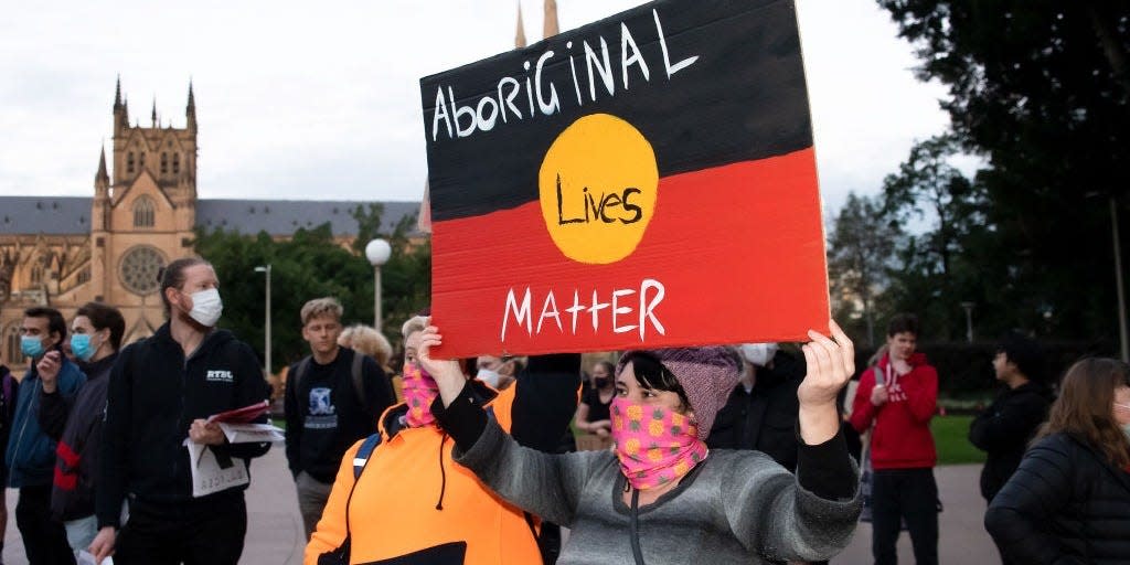 Protesters hold up signs in Hyde Park during a 'Black Lives Matter' rally on June 2, 2020, in Sydney, Australia.