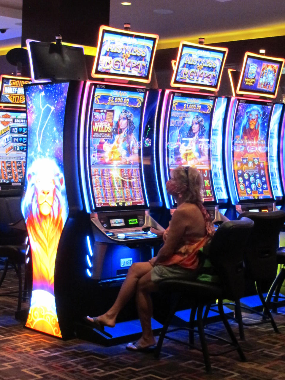 In this July 2, 2020 photo, a woman plays a slot machine at the Golden Nugget casino in Atlantic City N.J. Gambling companies in the U.S. are increasingly bringing different forms of gambling together, including sports betting, casino gambling, internet gambling and daily fantasy sports, and partnering with media companies as they seek to increase revenue. (AP Photo/Wayne Parry)