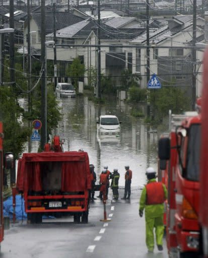 Emergency service personnel look at vehicles stranded in floodwaters along a street in Nagoya, Aichi prefecture, in central Japan. More than a million people in Japan were warned to leave their homes on Tuesday as an approaching typhoon brought heavy rain and floods which left three dead or missing