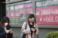People walk by an electronic stock board of a securities firm in Tokyo, Monday, March 1, 2021. Asian shares were higher on Monday on hopes for President Joe Biden’s stimulus package and bargain-hunting buying after the shares’ fall last week. (AP Photo/Koji Sasahara)