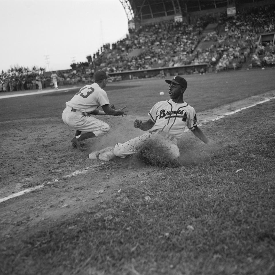 Aaron slides safely into third base in a game against the Brooklyn Dodgers in 1954 - Bettmann