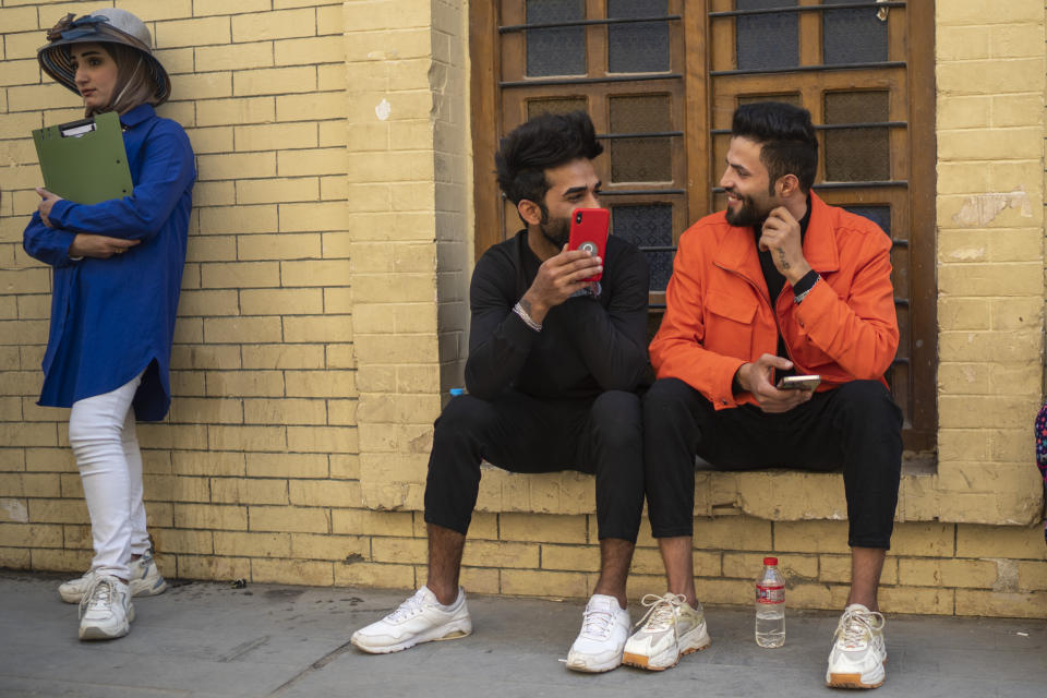 Young men chat near Al-Mutanabbi street in Baghdad, Iraq, Friday, Feb. 24, 2023. Two decades after a U.S.-led invasion, Iraq’s capital today is full of life and a sense of renewal, its residents enjoying a hopeful, peaceful interlude in a painful modern history. (AP Photo/Jerome Delay)