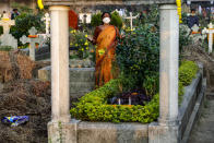 An Indian Christian woman wearing a face mask as a precaution against the coronavirus prays beside the grave of a deceased relative during All Souls Day in Kolkata, India, Monday, Nov. 2, 2020. (AP Photo/Bikas Das)