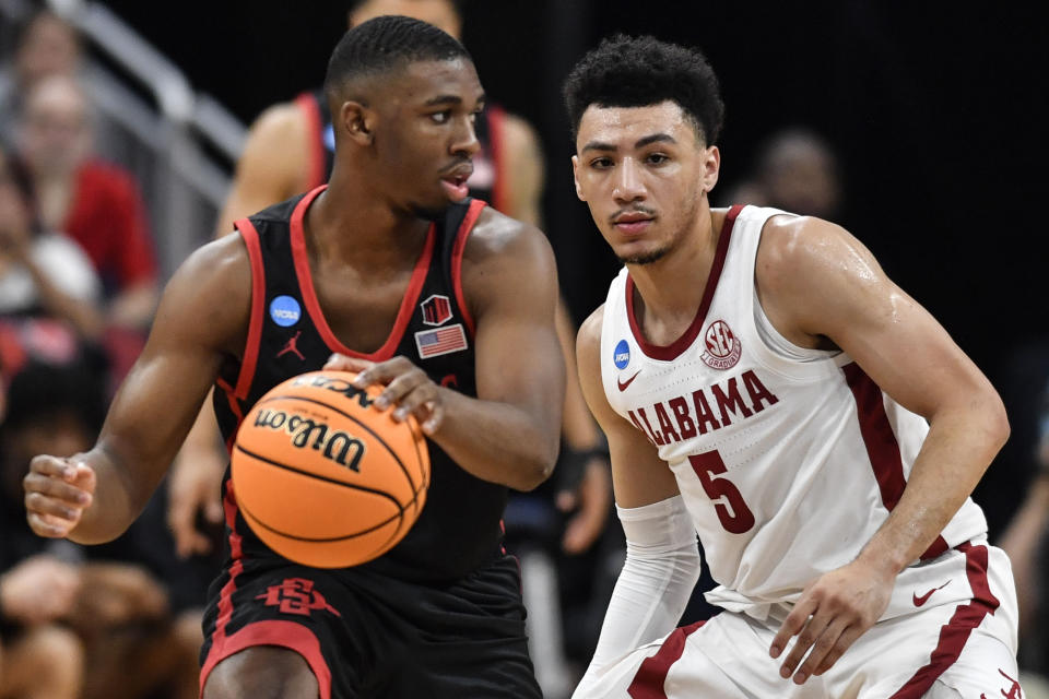 San Diego State guard Lamont Butler (5) moves the ball against Alabama guard Jahvon Quinerly (5) in the second half of a Sweet 16 round college basketball game in the South Regional of the NCAA Tournament, Friday, March 24, 2023, in Louisville, Ky. (AP Photo/Timothy D. Easley)