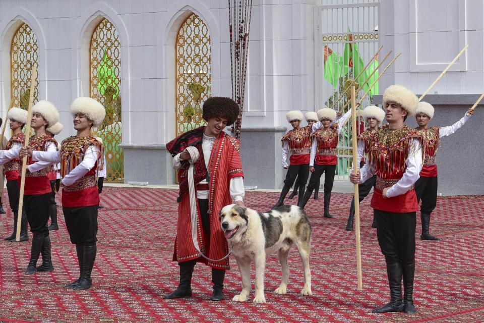 A man dressed in a national costume, center, pets his border guard shepherd dog Alabay during Dog Day celebration in Ashgabat, Turkmenistan, Sunday, April 25, 2021. The Central Asian nation of Turkmenistan has celebrated its new state holiday honoring the native Alabay dog breed. President Gurbanguly Berdymukhamedov established the holiday to be observed on the same day that Turkmenistan lauds its Akhla-Teke horse, a breed known for its speed and endurance. (AP Photo)