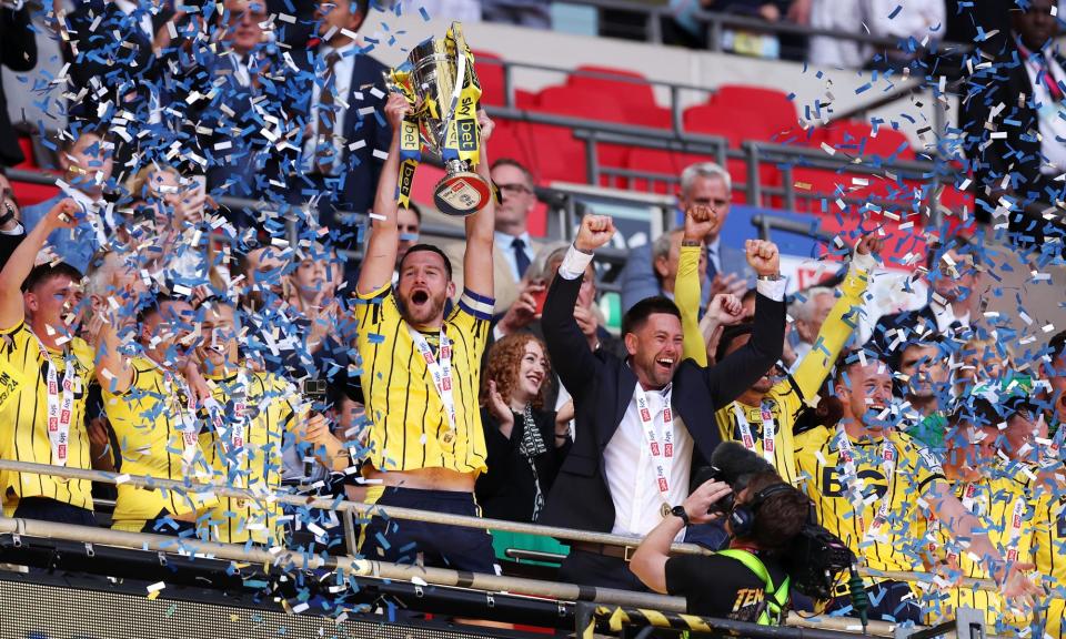 <span>Oxford’s Elliott Moore lifts the playoff final trophy after beating Bolton.</span><span>Photograph: Alex Pantling/Getty Images</span>