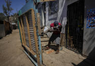 Haitian Edanold Delva, who has permanent residency in Chile, plays with his Chilean-born son Moises, 2, outside their home they share with Delva wife, Moises' mother, Jacqueline Michel, who also has residency, in the Bosque Hermoso camp settled by migrants in Lampa, Chile, Friday, Oct. 1, 2021. Most Haitians are fleeing earthquakes, hurricanes, political turbulence and poverty in their homeland. (AP Photo/Esteban Felix)