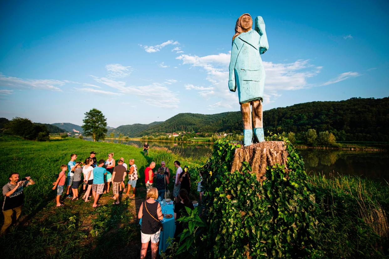 People gather around what conceptual artist Ales 'Maxi' Zupevc claims is the first ever monument of Melania Trump, set in the fields near the town of Sevnica, US First Ladys hometown, during a small inauguration celebration on July 5, 2019.