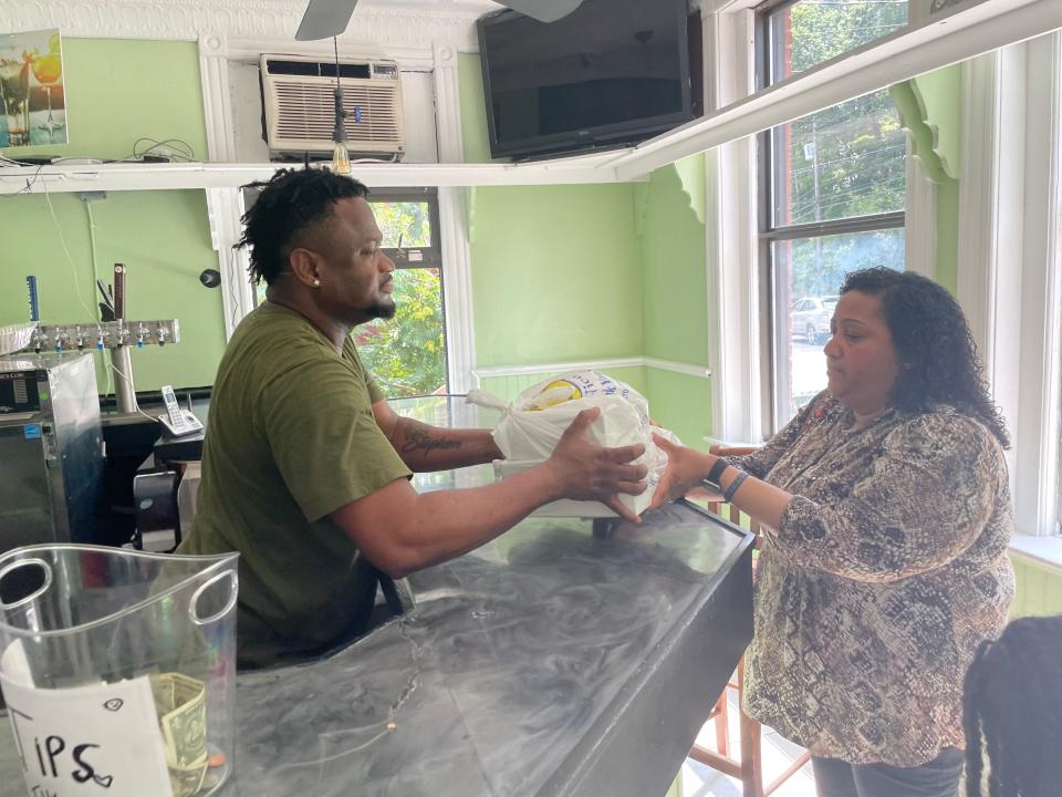 Palermo Bakery & Bar employee Philistin Joseph Jr. hands an order of patties to Norwich resident Celia Dulcine.