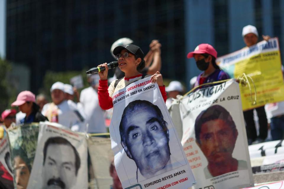 A woman holding a sign uses a microphone during a protest to mark the International Day of the Victims of Enforced Disappearances, in Mexico City, 