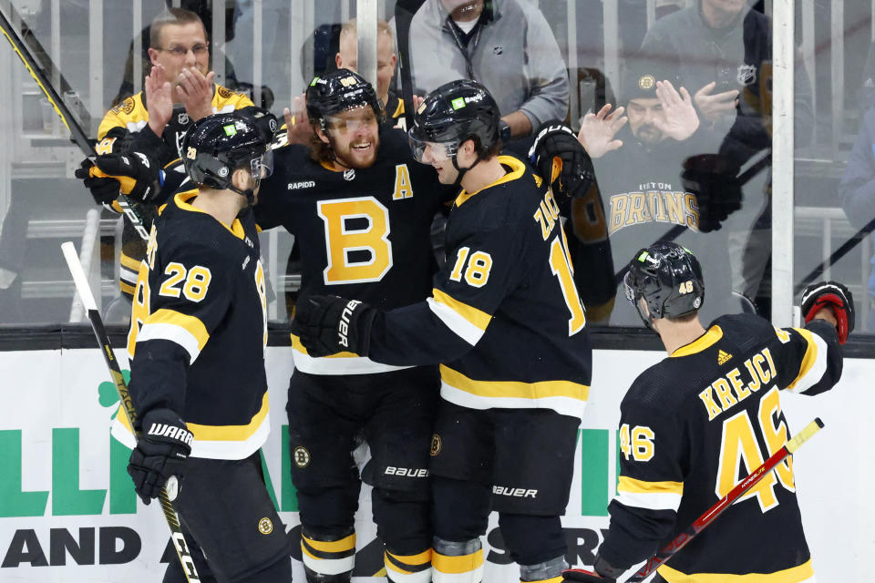 Boston Bruins right wing David Pastrnak, center, is congratulated by teammates Derek Forbort (28), Pavel Zacha (18), and David Krejci after scoring a goal during the first period of an NHL hockey game against the Philadelphia Flyers, Monday, Jan. 16, 2023, in Boston. (AP Photo/Mary Schwalm)