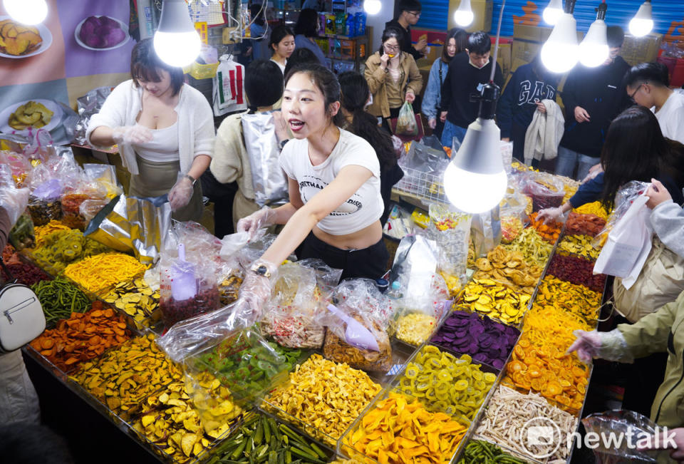 台北年貨大街賣年節應景甜食的工讀生賣力的向採購年貨的市民推銷他們的產品。   圖：張良一/攝