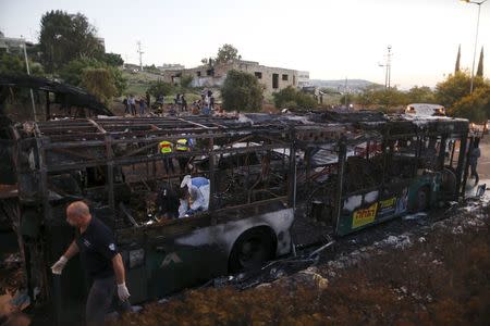 Israeli police forensic experts work at the scene after an explosion tore through a bus in Jerusalem on Monday and set a second bus on fire, in what an Israeli official said was a bombing, Israel, April 18, 2016. REUTERS/Ammar Awad