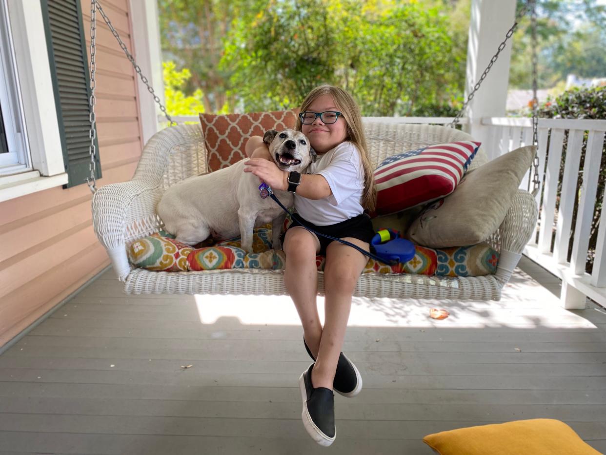 Ava Coulter sits on a swing on her porch with her dog, Jack