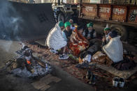 Farmers sit around a bonfire on a blocked highway in protest against new farm laws at the Delhi-Uttar Pradesh state border, outskirts of New Delhi, India, Wednesday, Jan. 20, 2021. Farmers have been blockading highways connecting New Delhi to northern India for nearly seven weeks against new farm laws, obstructing transportation and dealing a blow to manufacturing and businesses in the north. Farmers fear the government will stop buying grain at minimum guaranteed prices and that corporations will then push prices down under the new laws. (AP Photo/Altaf Qadri)