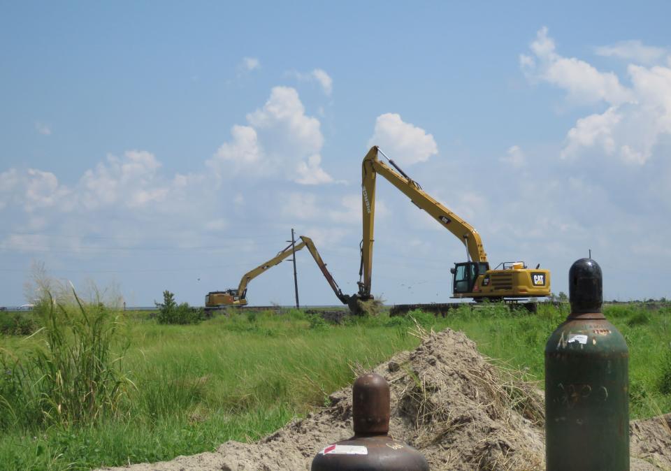 Excavators work on a Louisiana barrier island on Wednesday, July 28, 2021, creating berms to guide the placement of sand pumped from a dredge about five miles away. Contractors are at work on a $102 million Louisiana Coastal Restoration and Protection Authority project to add about 400 acres of beach, dune and marshland to Grand Terre Island. Weather permitting, they hope to finish in November. (AP Photo/Janet McConnaughey)