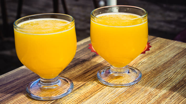 Two yellow drinks on a wooden table 