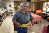 Ruben Hernandez, owner of the Buckshot Restaurant in Niland, Calif., serves dinner Thursday, July 15, 2021. The community on the shore of the shrinking Salton Sea has been through decades of economic stagnation. Now, the area is at the forefront of efforts to make the U.S. a major global producer of lithium, the ultralight metal used in rechargeable batteries. Hernandez says backers of the project who come for breakfast tell him he could eventually be feeding 20 to 30 people and delivering lunches to their plant. (AP Photo/Marcio Jose Sanchez)