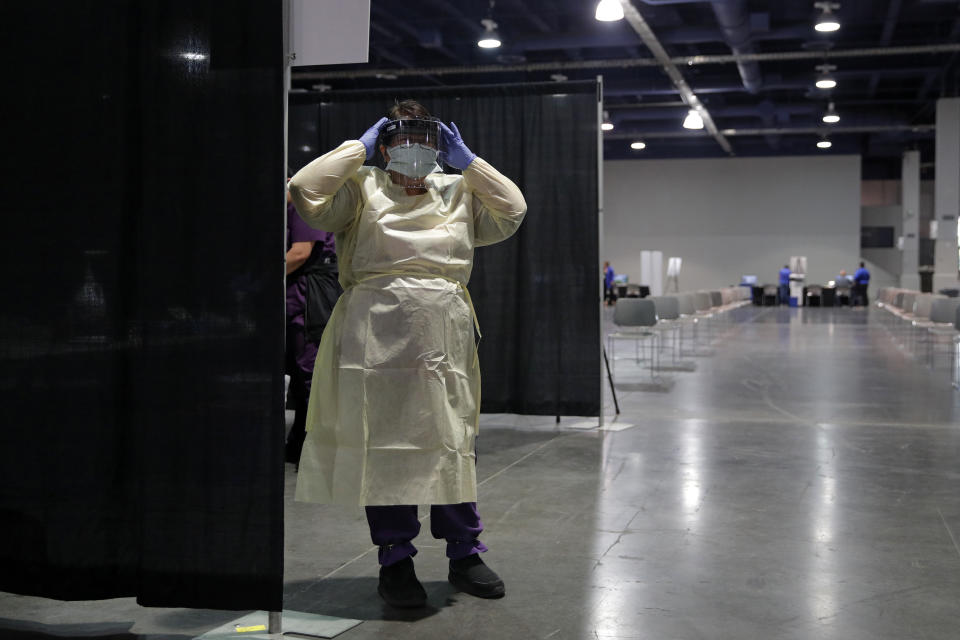 FILE - In this May 21, 2020 file photo a nurse dons personal protective equipment before the opening of a temporary coronavirus testing facility for casino employees at the Las Vegas Convention Center, in Las Vegas. Health officials in Las Vegas say they hope to administer more than 1,000 doses of coronavirus vaccine a day to area residents once a big drive-thru COVID-19 shot clinic opens Tuesday, May 4, 2021, at the Las Vegas Convention Center. (AP Photo/John Locher,File)