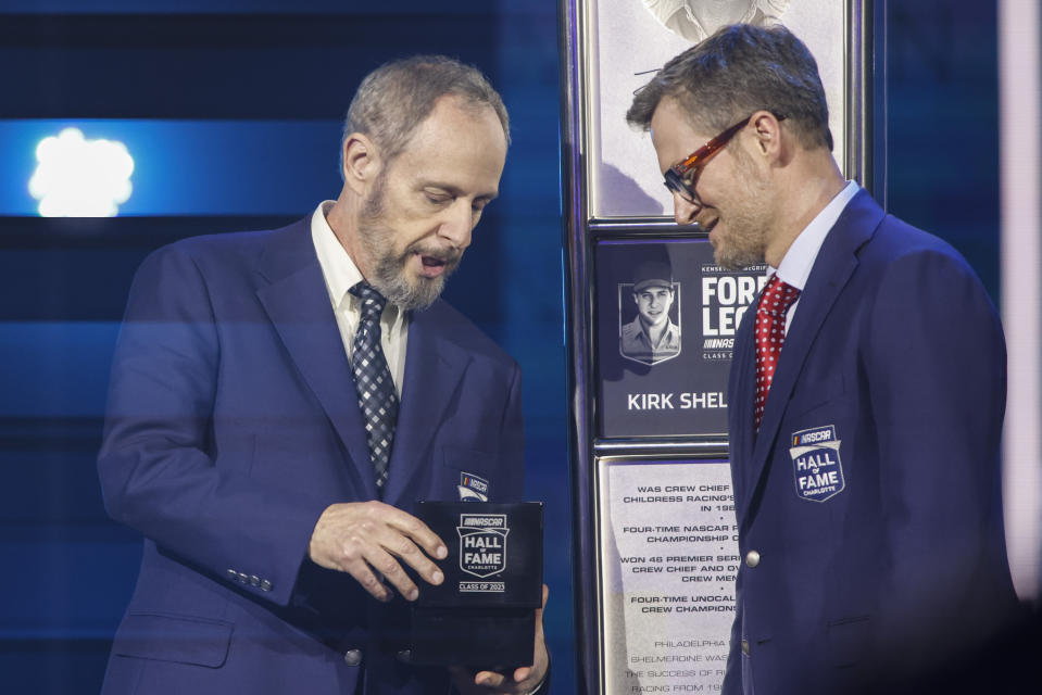 Kirk Shelmerdine, left, looks at his ring presented to him by Dale Earnhardt Jr. as Shelmerdine is inducted into the NASCAR Hall of Fame in Charlotte, N.C., Friday, Jan. 20, 2023. (AP Photo/Nell Redmond)