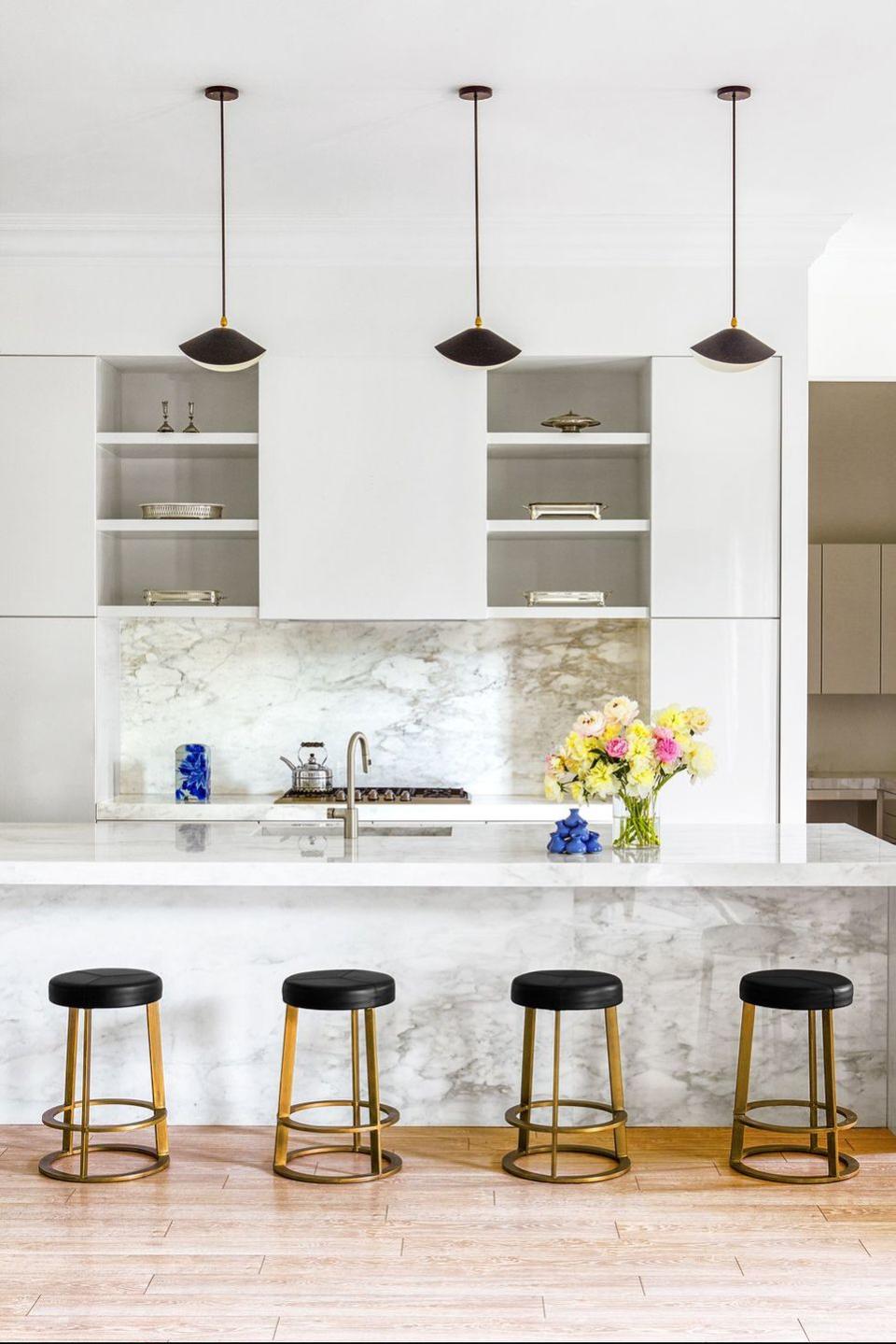 <p>When Raji Radhakrishnan was commissioned to decorate this kitchen in a Piet Boon-designed home, he didn't want to detract from the beautiful architectural details. To preserve as much as possible, he opted for a trio of Serge Mouille pendants and simple backless stools from West Elm. Oh, and one of the best things about minimalist kitchens is that your flowers can really pop.</p>