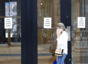 A woman walks by a closed store, in London, Thursday, July 16, 2020. Unemployment across the U.K. has held steady during the coronavirus lockdown as a result of a government salary support scheme, but there are clear signals emerging that job losses will skyrocket over coming months. The Office for National Statistics said Thursday there were 649,000 fewer people, or 2.2%, on payroll in June when compared with March when the lockdown restrictions were imposed. (AP Photo/Alastair Grant)