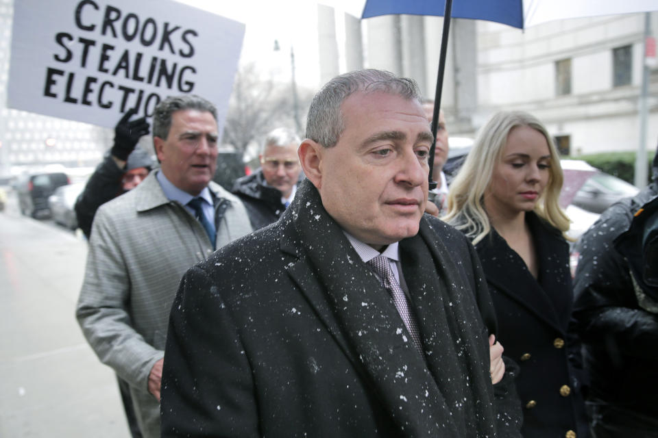 A man holds a sign in the street as Lev Parnas arrives to court in New York, Monday, Dec. 2, 2019. Parnas and Igor Fruman, close associates to U.S. President Donald Trump's lawyer Rudy Giuliani, were arrested last month at an airport outside Washington while trying to board a flight to Europe with one-way tickets. They were later indicted by federal prosecutors on charges of conspiracy, making false statements to the Federal Election Commission and falsification of records. (AP Photo/Seth Wenig)