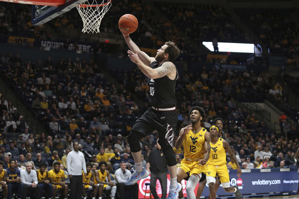 Eastern Kentucky guard Braxton Beverly, center, is shoots while defended by West Virginia guards Taz Sherman (12) and Malik Curry, right, during the first half of an NCAA college basketball game in Morgantown, W.Va., Friday, Nov. 26, 2021. (AP Photo/Kathleen Batten)