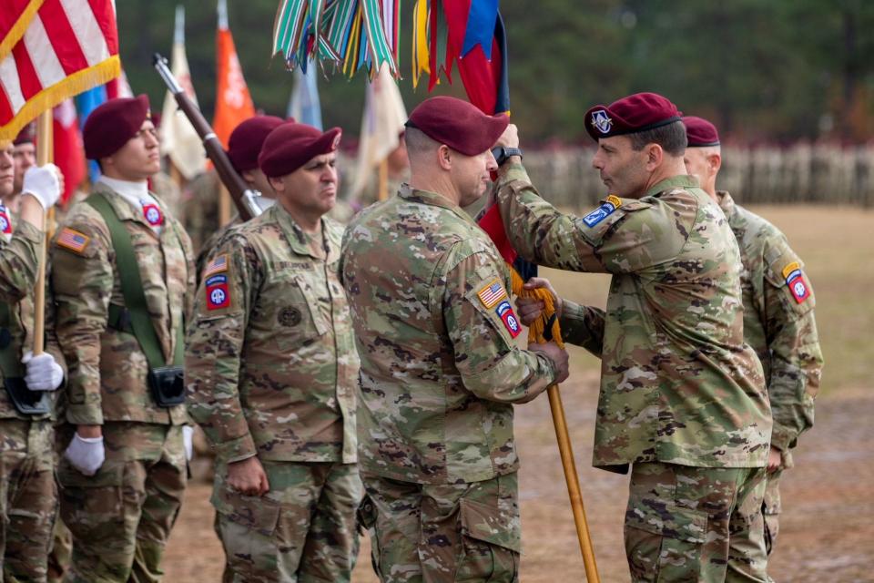 Brig. Gen. Patrick Work left, receives the 82nd Airborne Division colors from Lt. Gen. Christopher Donahue, right, 18th Airborne Corps commander, during a command change ceremony Friday, Nov. 17, 2023, on Pike Field at Fort Liberty.