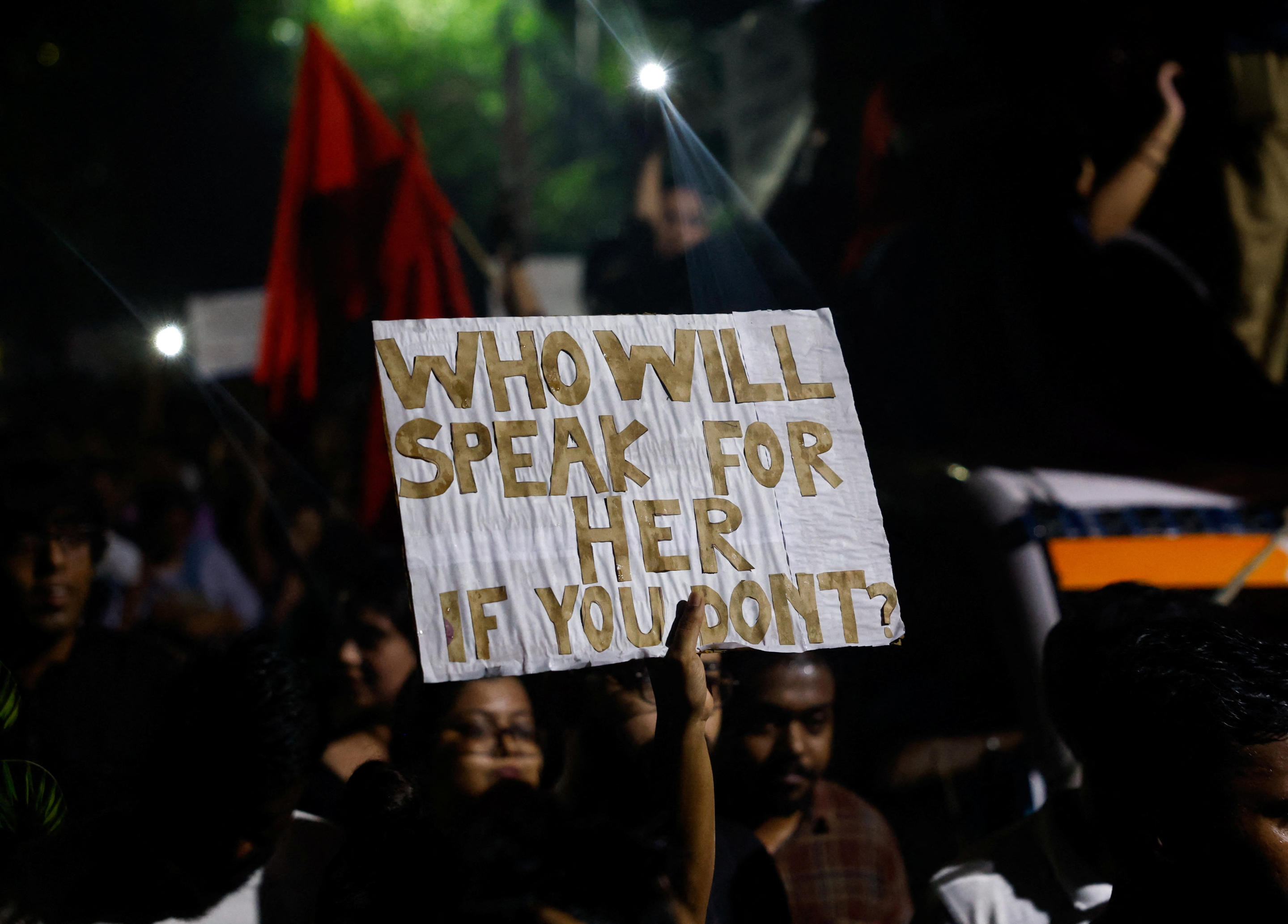 A woman holds a sign as she attends a candlelight vigil outside the campus of Jadavpur University in Kolkata, India on Wednesday.