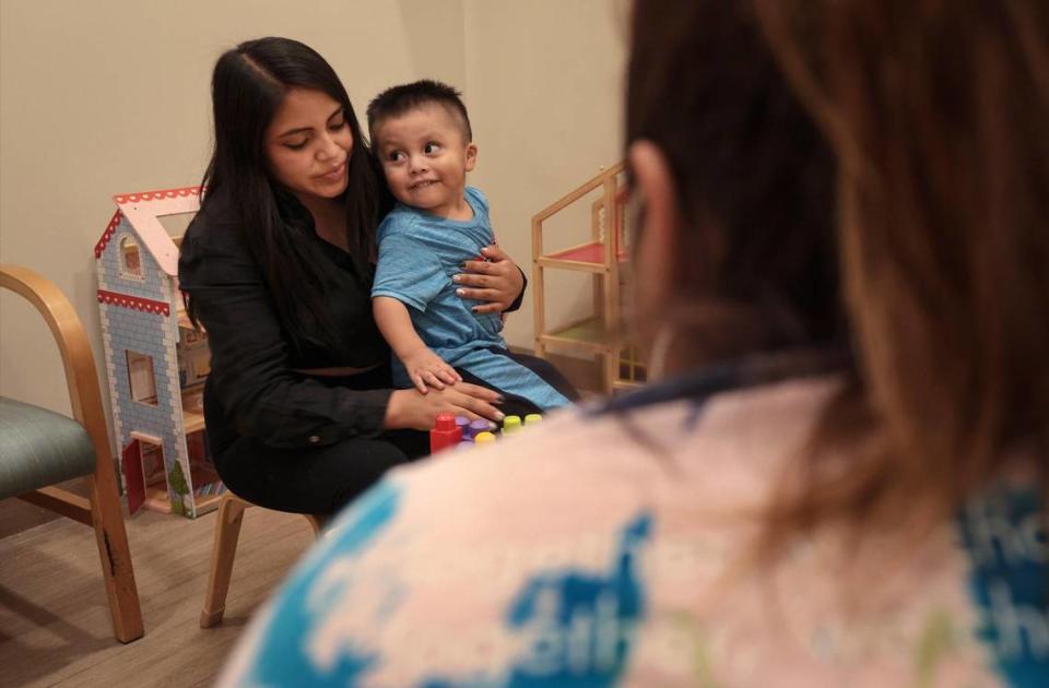 Darwin López, de dos años, al centro, y su madre, Teresa López, de 19, juegan juntos durante la terapia de interacción entre padres e hijos en Lotus Village.