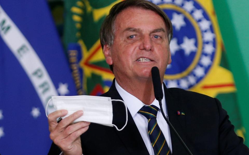 Brazil's President Jair Bolsonaro holds his protective face mask  - Reuters
