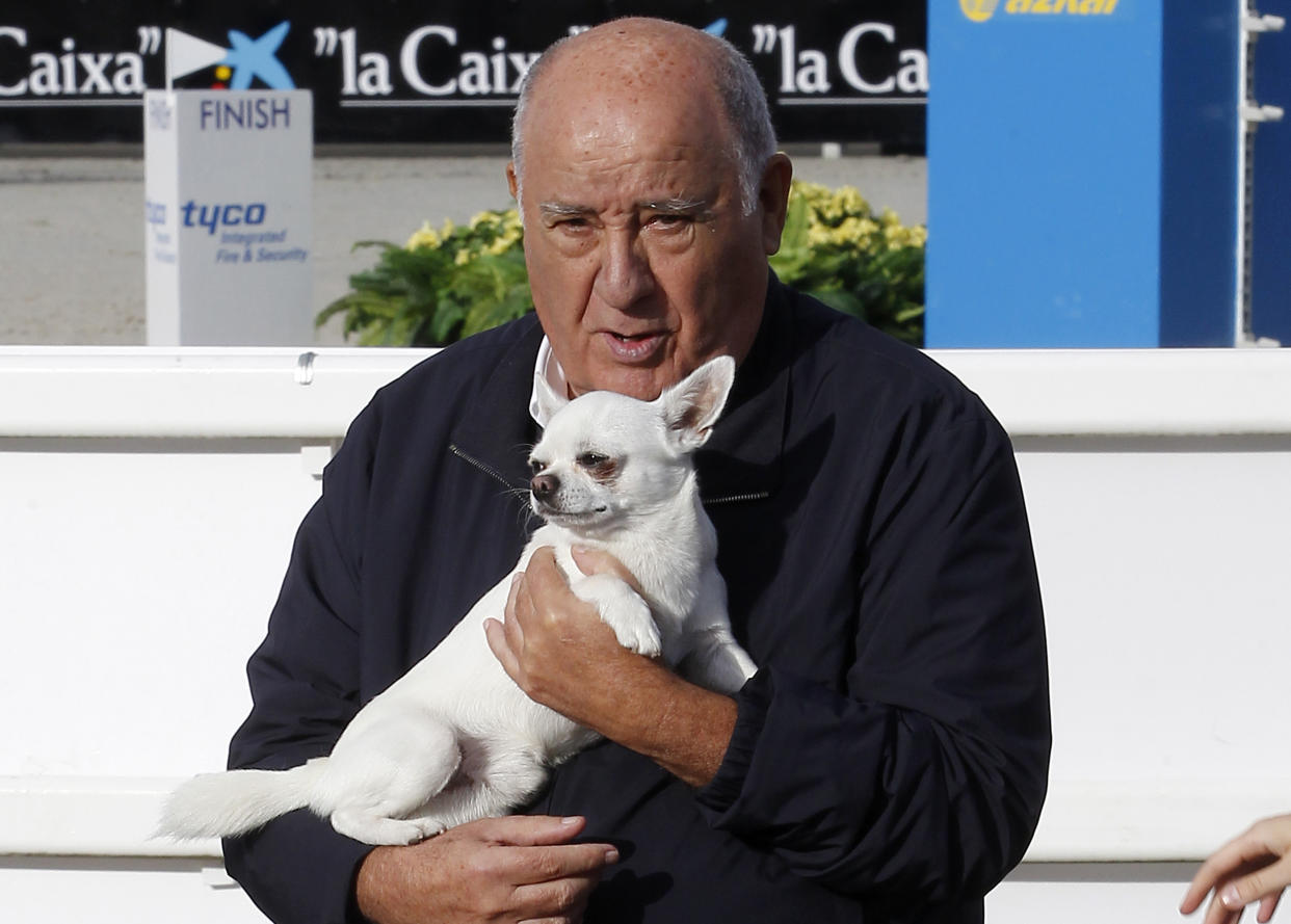 In this July 28, 2013 photo, Amancio Ortega Gaona, founding shareholder of Inditex fashion group, best known for its chain of Zara clothing and accessories retail shops, holds a dog during the Casas Novas International Jumping Show in Arteixo, A Coruña, in the Galicia region of northwest Spain. Amancio Ortega, has been named as the richest person in Europe, and the second richest in the whole world. (AP Photo/Iago Lopez)