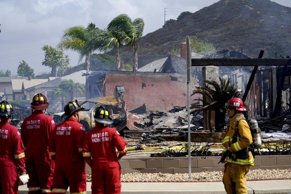 Fire crews work the scene of a small plane crash, Monday, Oct. 11, 2021, in Santee, Calif. At least two people were killed and two others were injured when the plane crashed into a suburban Southern California neighborhood, setting two homes ablaze, authorities said. (AP Photo/Gregory Bull)