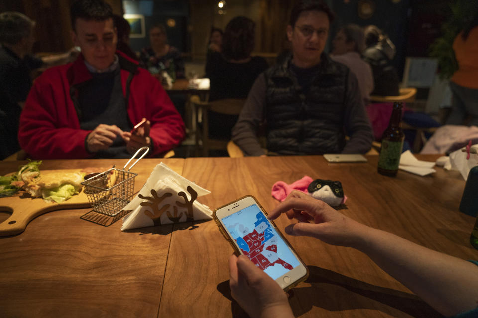 Attendees monitor electoral maps on their mobile phones during an election watch event held by Democrats Abroad at a restaurant in Beijing, China on Wednesday, Nov. 4, 2020. President Donald Trump and his Democratic challenger, Joe Biden, are in a tight battle for the White House. (AP Photo/Ng Han Guan)