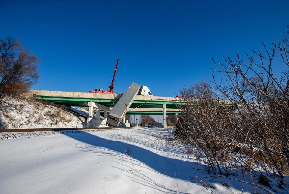 A FedEx semi comes to rest over train tracks after its trailer toppled over an Indiana Toll Road bridge on Interstate 80/90, at Currant Road, on Wednesday, Jan. 26, 2021, in Mishawaka. Near zero temperatures and icy roads caused multiple accidents in the area on Wednesday morning.