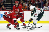 Minnesota Wild's Jordan Greenway (18) is challenged by Carolina Hurricanes' Jordan Martinook (48) with Jaccob Slavin (74) nearby during the second period of an NHL hockey game in Raleigh, N.C., Thursday, Jan. 19, 2023. (AP Photo/Karl B DeBlaker)