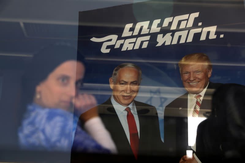FILE PHOTO: An ultra-orthodox Jewish woman is seen through a bus window along with a reflection of a Likud party election campaign banner depicting Israeli Prime Minister Benjamin Netanyahu and U.S. President Donald Trump in Bnei Brak, Israel