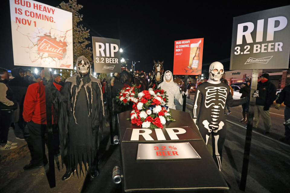 A ghoulish group of pallbearers stand in front of a casket representing 3.2% beer, Wednesday, Oct. 30, 2019, in Salt Lake City. After 86 years, this Halloween marks the last day 3.2% beer will be sold in Utah stores. Beginning Nov. 1, Utah stores will be selling up to 5% ABV beer, and Budweiser wants to celebrate with a funeral complete with their famous Clydesdales, in the background. (AP Photo/Rick Bowmer)
