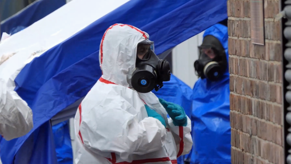 Police officers in protective suits at scene of illegal drug factory