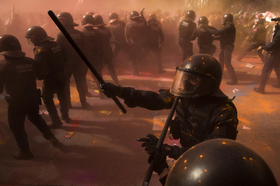 Catalan police officers clash with pro independence demonstrators on their way to meet demonstrations by members and supporters of National Police and Guardia Civil, as coloured powder is seen in the air after being thrown by protesters, in Barcelona on Saturday, Sept. 29, 2018. (AP Photo/Emilio Morenatti)